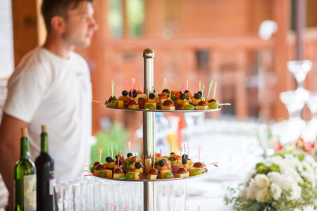Little pieces of fruits and cheese stand behind the bottle of wineの写真素材