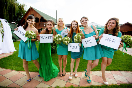 Attractive bridesmaids in green dresses hold printed lettering in their handsの写真素材