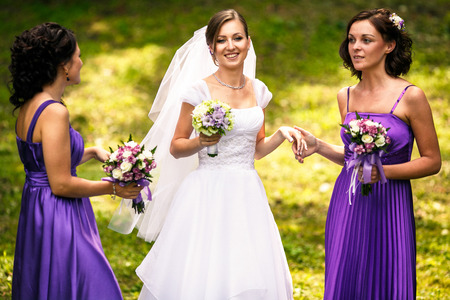 Bridesmaid in a violet dress holds bride's hand while talkingの写真素材