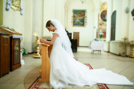 Bride prays on the knees standing in the front of an icon in the churchの写真素材