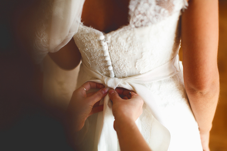 Hands put on a bow on delicate bride's waistの写真素材