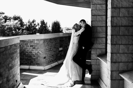 Bride kisses a groom who leans to the wall on the balconyの写真素材