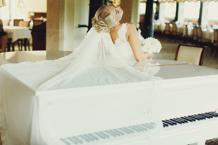 Bride bends over a piano and her veil spreads over itの写真素材