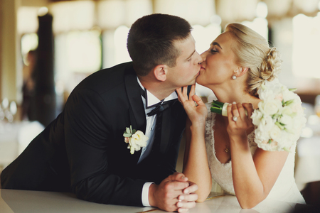 Bride and groom kiss leaning on the pianoの写真素材