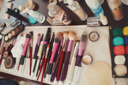 Make-u brushes lie between eye-shadows and tools on a tableの写真素材