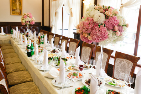 Long dinner table decorated with pink flowers in high vasesの写真素材