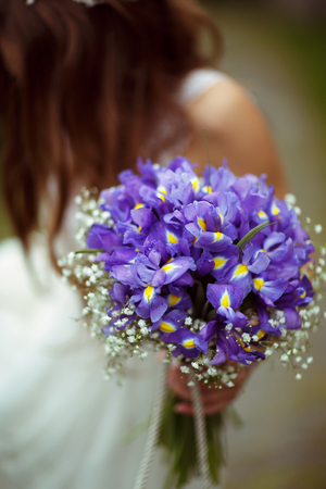 A bouqet of violet crocuses is held by a brideの写真素材