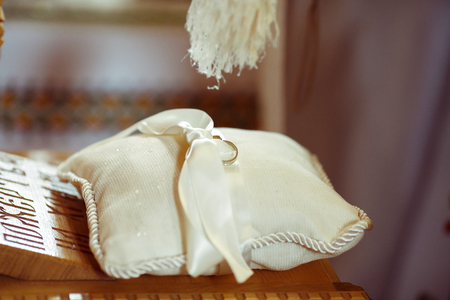 Priest blesses a wedding rings lying on a white pillowの写真素材