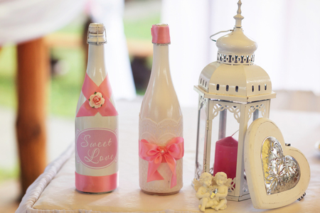 Champagne in white bottles stand behind a  white lantern with red candleの写真素材