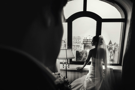 Bride waits for a groom standing in the front of a big windowの写真素材