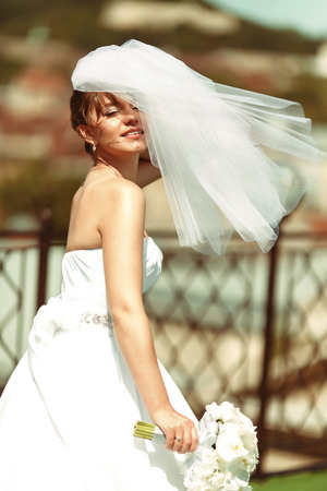 Pretty bride enjoys wind on the roof in a sunny weatherの写真素材