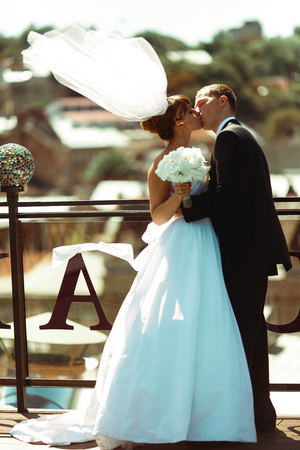 Happy wedding couple kisses on the roof in a windy weatherの写真素材
