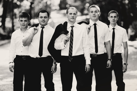 A black and white picture of groomsmen and groom posing in the parkの写真素材