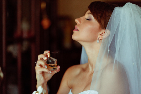 Stunning bride adjusts perfumes on her tender neckの写真素材