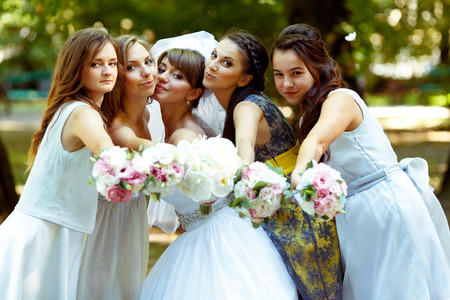 Bride and bridesmaids reach hands with bouquets to the cameramanの写真素材