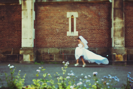 Bride runs along the brick wallの写真素材