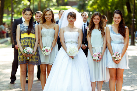 Bride and girl stand in the ray posing in the parkの写真素材