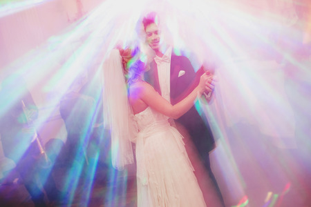 Bride and groom look like the angels dancing in the bright rays of disco lightsの写真素材