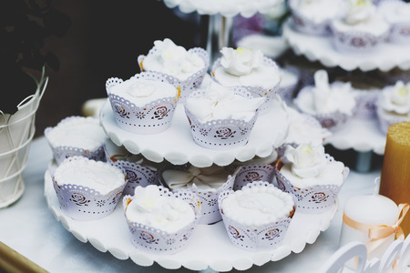 Cupcakes covered with white glaze stand on the tired dish
