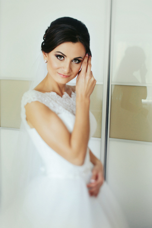 Bride with big deep eyes poses in a white roomの写真素材