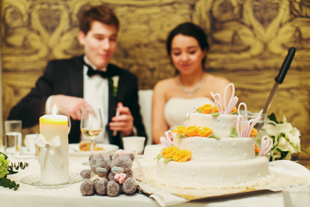 Little gray teddy bears stand on the table behind a wedding cakeの写真素材