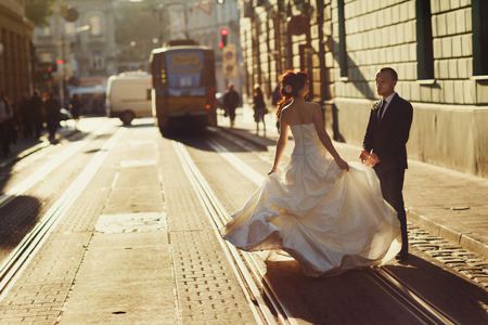Bride holds her dress up while standing with a groom on the tramwaysの写真素材