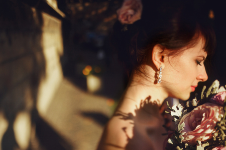 Bride's skin shines while she holds a bouquet behind her neckの写真素材