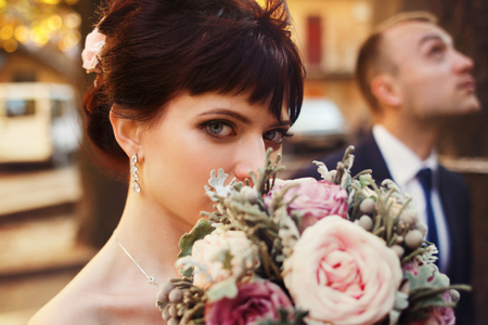 Blue-eyed brunette bride hides her face behind a wedding bouquetの写真素材
