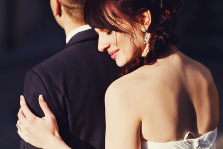 Delicate leans to groom's shoulder hugging him from behindの写真素材