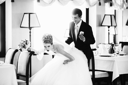 Bride downs leaning to a groom in an empty restaurant hallの写真素材