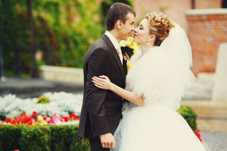 Bride and groom touch each other noses standing in the gardenの写真素材