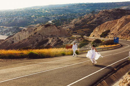 Happy wedding couple walks along the highwayの写真素材