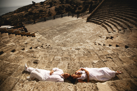 Bride and groom lie on the stone footsteps  in an old open air theatreの写真素材