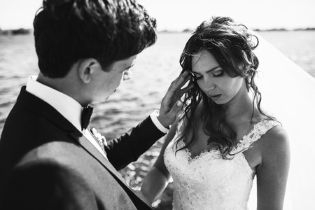 Groom adjusts bride's hair touching her face tenderlyの写真素材