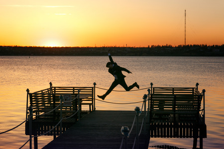 Happy man jumps up on the bridge on a estuary shoreの写真素材