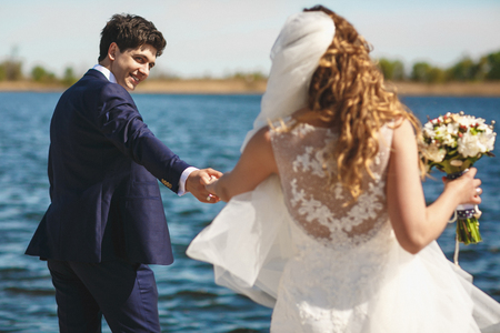 Groom looks at a bride over his shoulder holding her hand tightlyの写真素材
