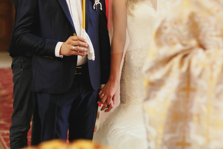 Married couple hold each other hands tightly during the ceremony in churchの写真素材