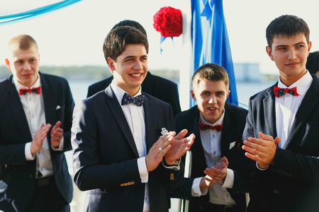 Groom and groomsmen wait for a bride behind a wedding altarの写真素材