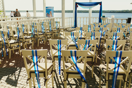 Chairs stand behind a wedding altar on the estuaryの写真素材