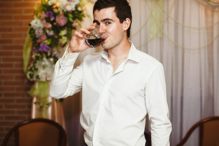 Groom is drinking a whiskey on the wedding celebrationの写真素材