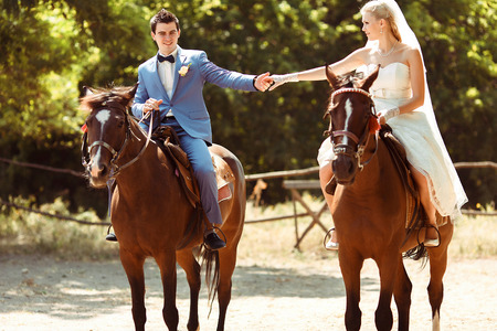 Groom and bride are riding horses togetherの写真素材