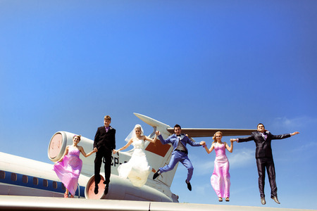 Newlyweds with friends and a plane behindの写真素材