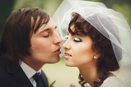 A bright picure of a groom reaching tender bride's face for a kissの写真素材