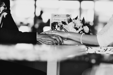 Black and white picture of newlyweds hands lying on the cafe tableの写真素材