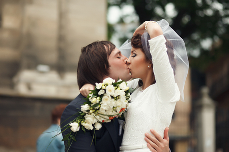 Groom leans to himself a gracious bride kissing herの写真素材