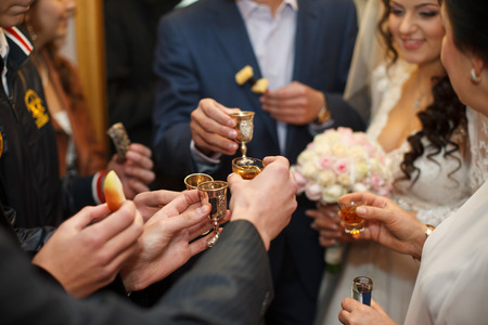 A closeup of guests' hands while they clang glasses with newlywedsの写真素材