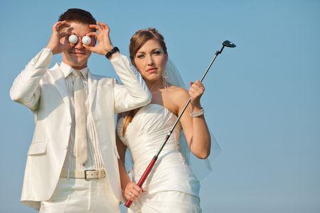 Bride and groom pose with golf stuff in a sunny dayの写真素材