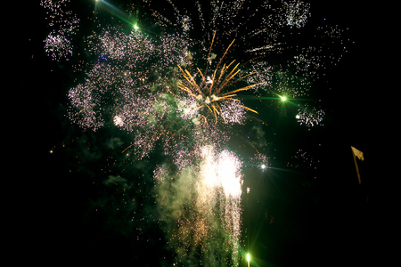 Green and white fireworks blow up illuminating night skyの写真素材