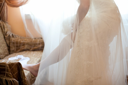 Bride in wedding dress puts on a stockingの写真素材