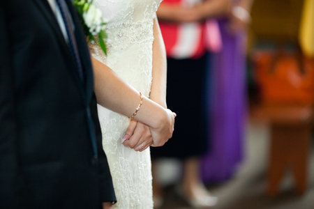 Bride holds her hands closed during the ceremony in churchの写真素材